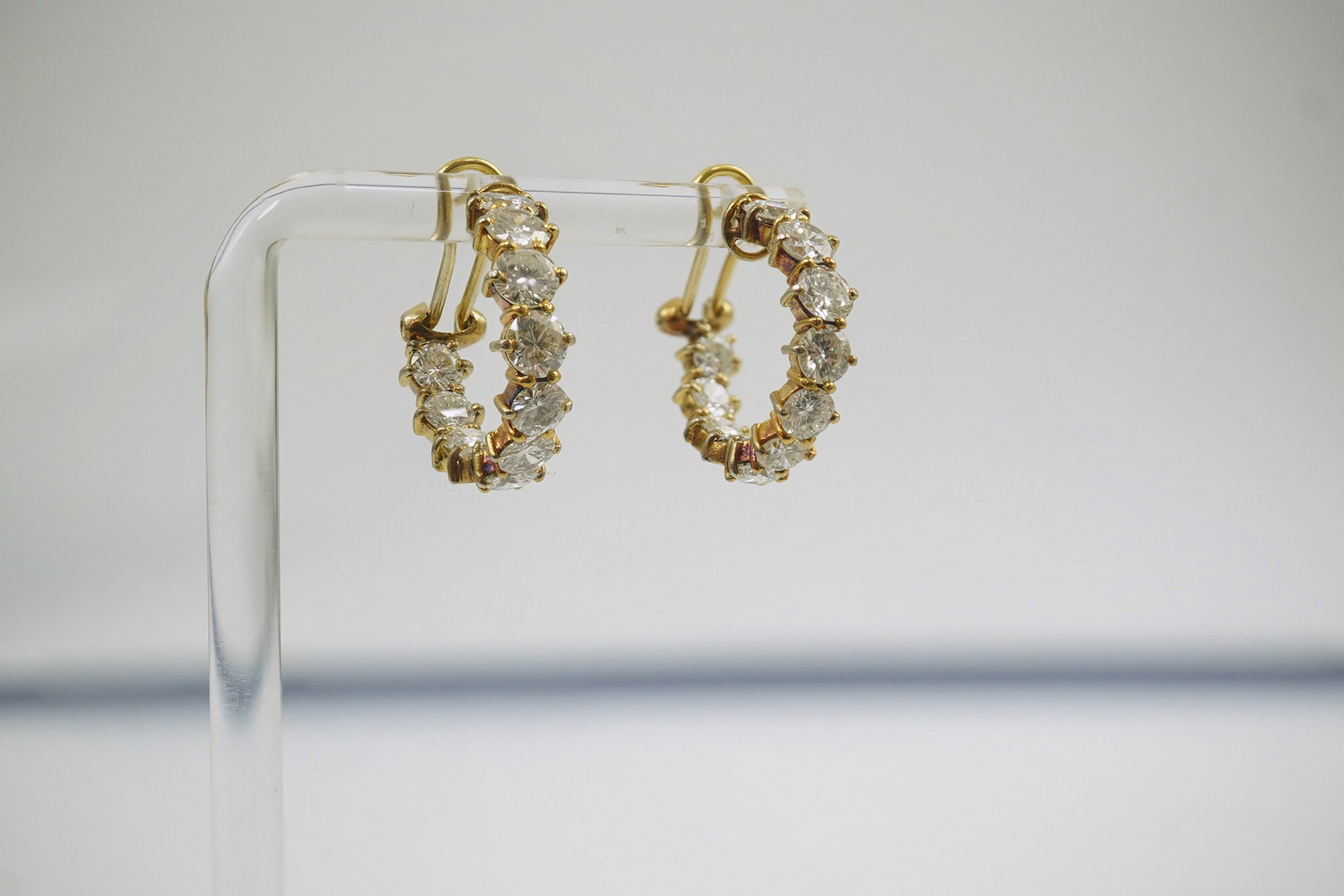 A modern pair of 18ct gold and graduated eleven stone round brilliant cut diamond set hoop earrings